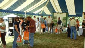 Field Day visitors enjoying exhibits under large tent