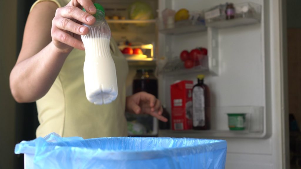 Photo of someone throwing away a bottle of milk