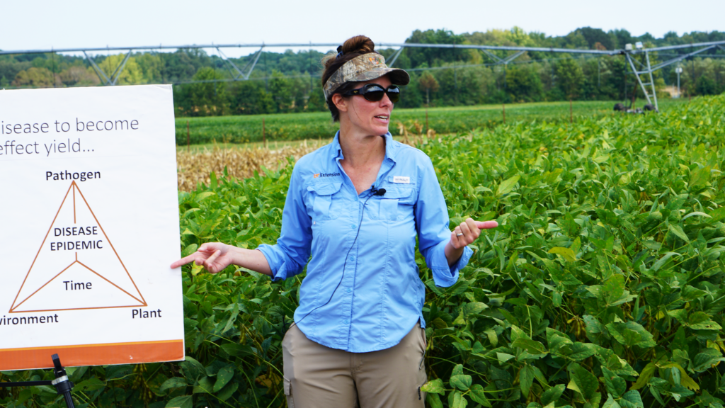 A researcher standing in a field with a chart giving a presentation